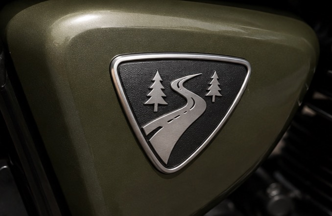 Road and trees shield badge on olive green motorcycle tank
